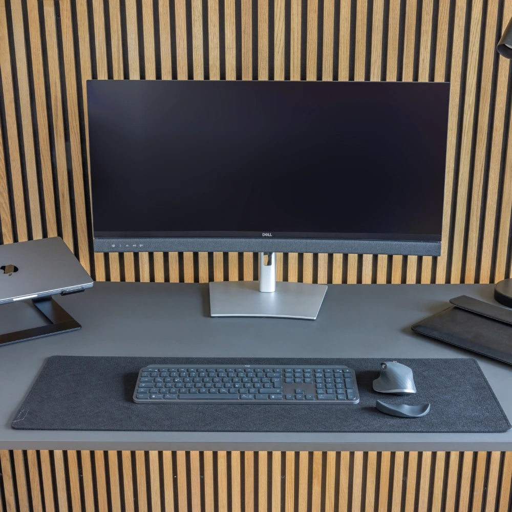 Moderner Schreibtisch mit einem Dell-Monitor, schwarzer FELTDESK Schreibtischunterlage, Tastatur, Maus und ergonomischer Handgelenkauflage. Die hochwertige Filzunterlage bietet eine stilvolle, rutschfeste Arbeitsfläche und trägt zu einem organisierten Arbeitsplatz bei.